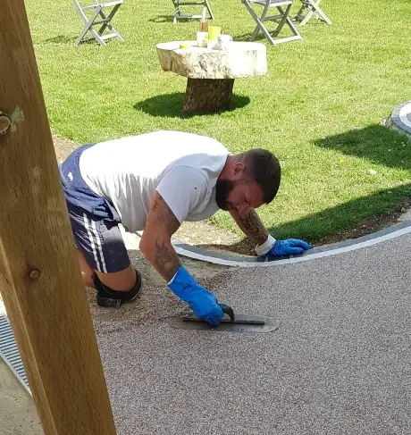 A man is working on a new resin surface, using tools to ensure a level and polished finish